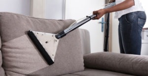man steam cleaning upholstery couch